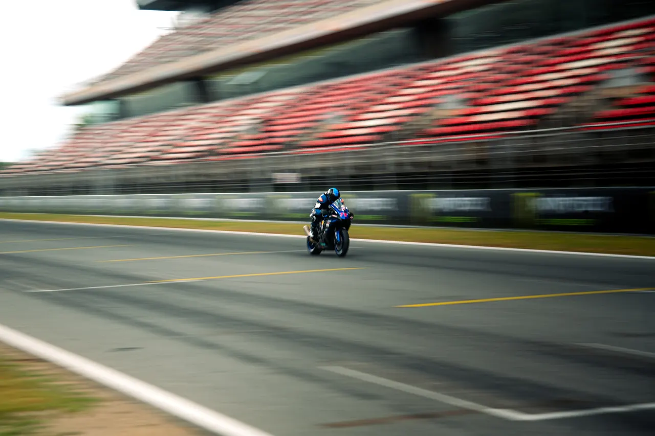 Moto en un circuit amb les grades desenfocades pel moviment.